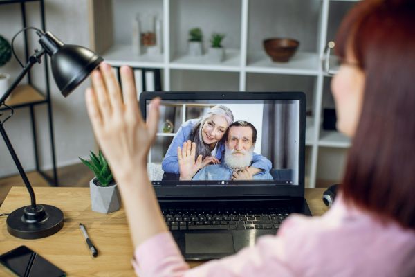 Young woman waving her hand during a video chat with her parents