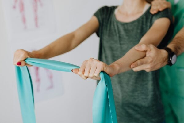 An intern helping a patient stretch using an elastic band.