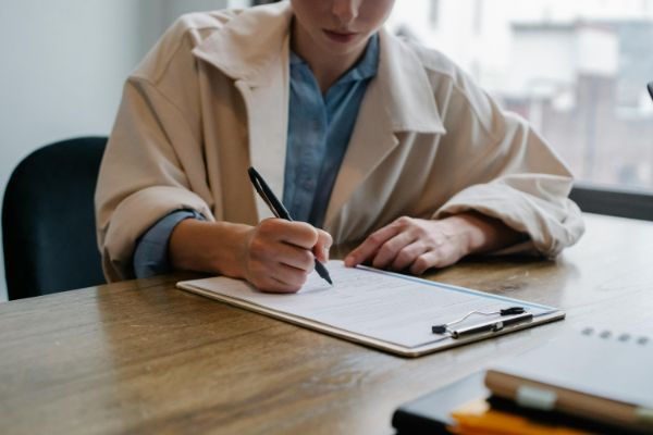 pexels-sora-shimazaki-5668869 (1) A woman writing on a piece of paper at her desk.