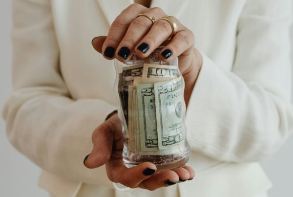 a woman in a white suit holding a jar of money