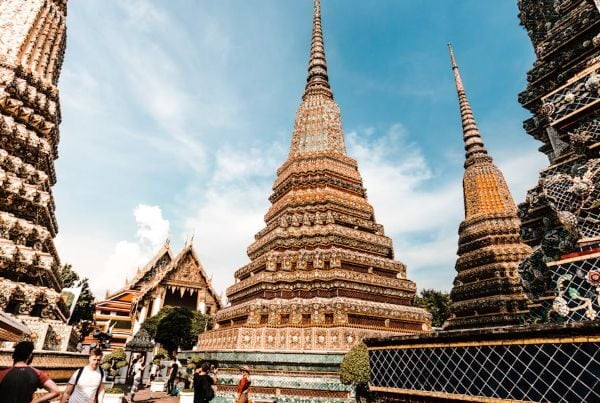 Tourists walking among ornate temple spires at Wat Pho in Bangkok