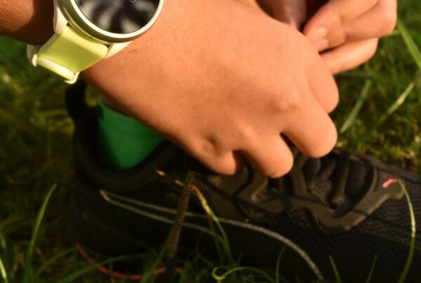 hands tying shoes next to yellow dumbbell