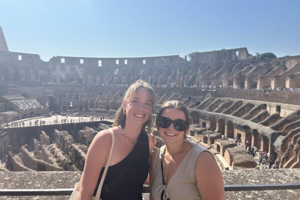 Two women standing in front of ancient ruins.
