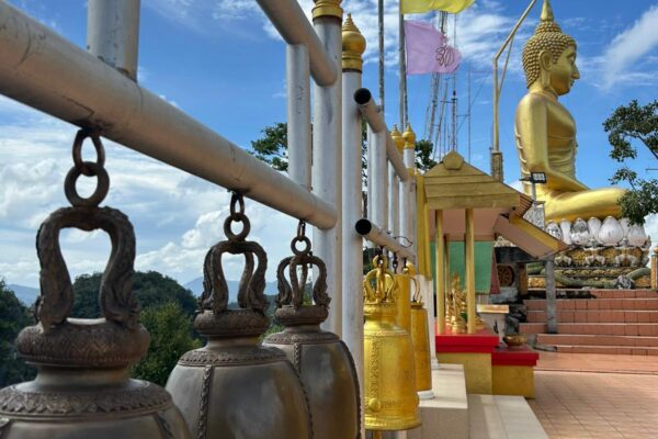 A paved path leading to a large golden Buddha statue.