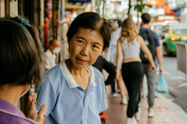 Two women talking while standing on the sidewalk in Thailand.